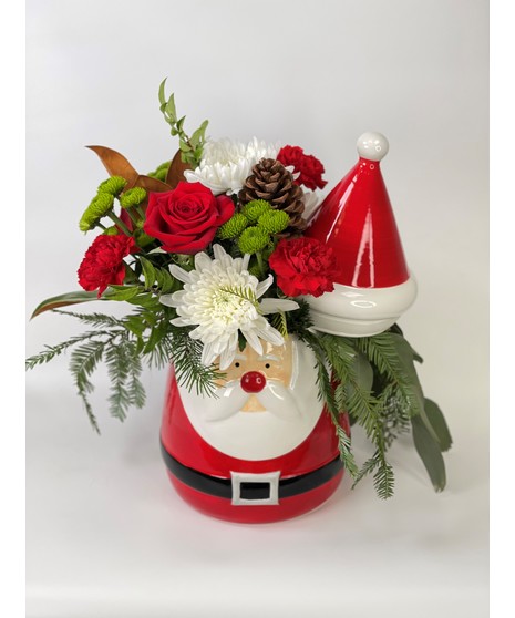 Santa's Treasure statue with evergreens and red and white flowers