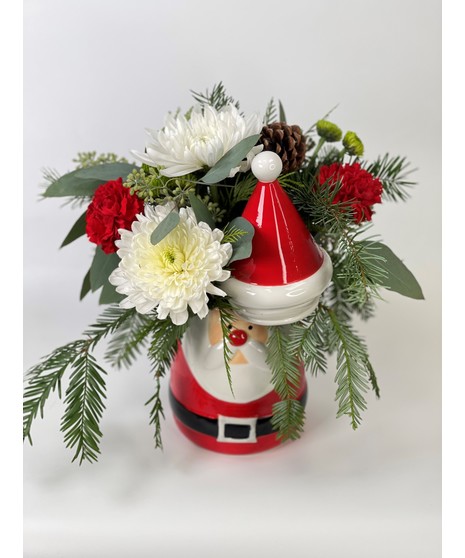 Santa's Treasure statue with evergreens and red and white flowers